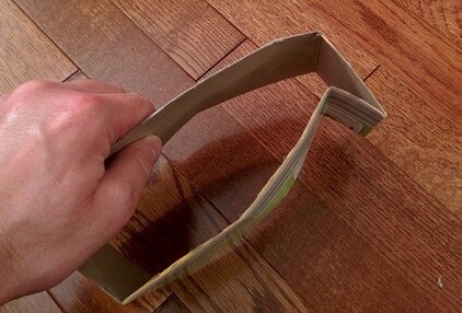 Hand forms cardboard base for DIY collapsible dog food bowl.